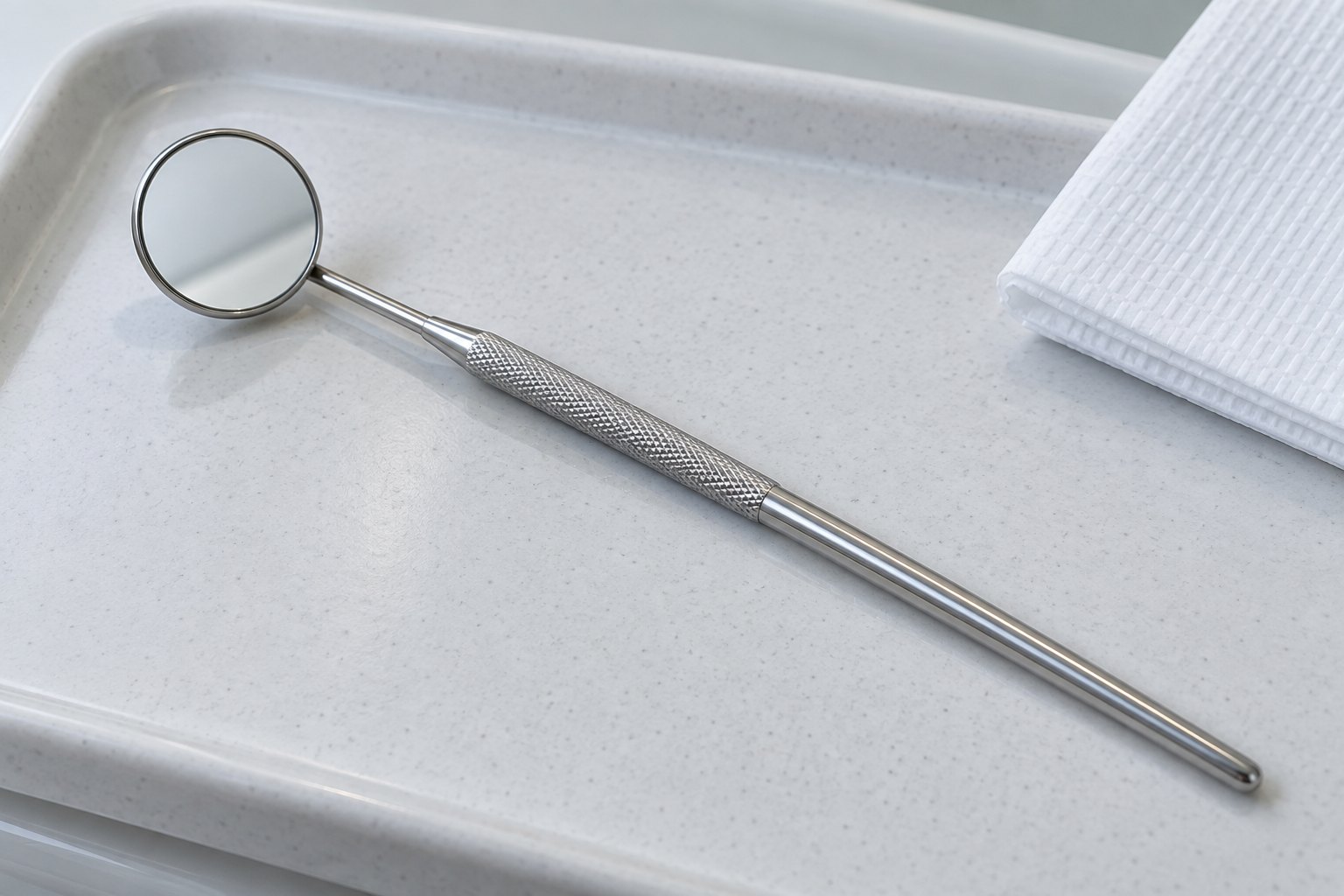 A dental mirror resting on a clean examination tray
